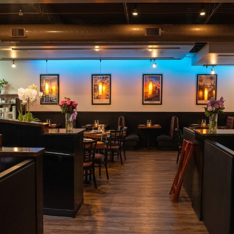 Inviting restaurant dining room with set tables, booths, wall art, and blue accent lighting.