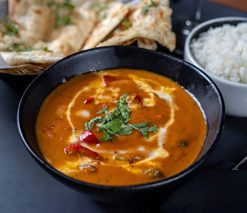 Indian curry with red peppers and cilantro, served with naan bread and white rice.